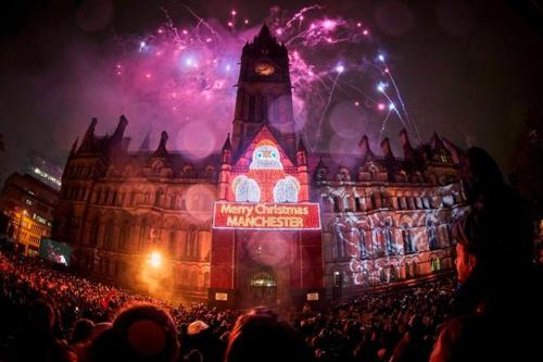 a crowd of people in front of a clock tower with fireworks at Media City Salford Quays in Manchester