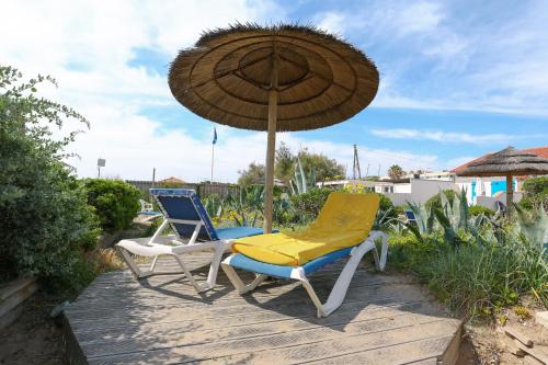 2 chaises et un parasol sur une terrasse en bois dans l'établissement Au Grand sud, à Hyères