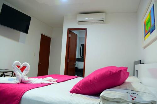 a bedroom with a bed with pink and white pillows at Hotel Aguazul Plaza Centro in Aguazul