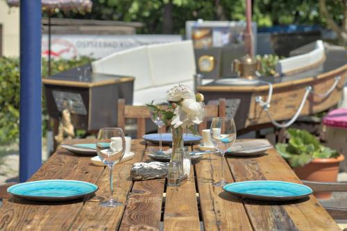 a wooden table with plates and wine glasses on it at feels Beach Club Hotel in Kühlungsborn