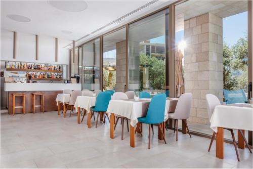 a dining room with white tables and blue chairs at Hotel Eleven in Petrovac na Moru