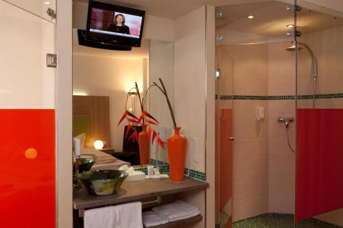 a bathroom with a shower and a tv on the wall at Hotel Aviva in Karlsruhe