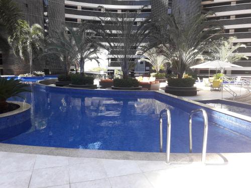 a large swimming pool in a building with palm trees at Maravilhoso Apartamento na Beira Mar in Fortaleza