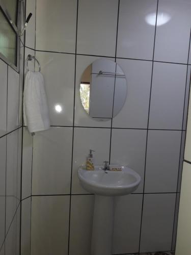 een wit betegelde badkamer met een wastafel en een spiegel bij Siqueira, aluguéis para temporadas in Paraty