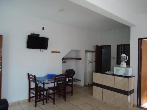 a kitchen with a table and chairs and a television at Chales Ubatuba I in Ubatuba