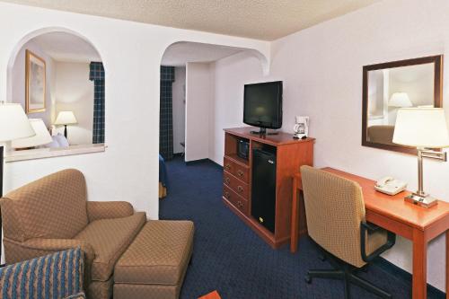 a hotel room with a desk and chairs and a television at Ramada by Wyndham Santa Fe in Santa Fe