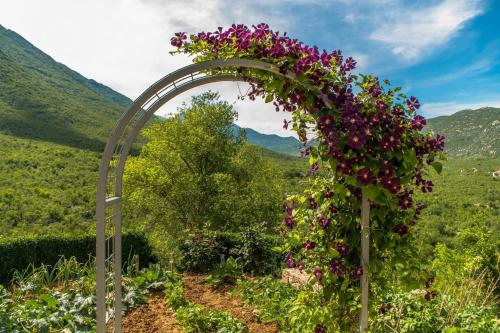 un arco ricoperto di fiori in un giardino di Holiday Home Godinj a Donje Rašćane