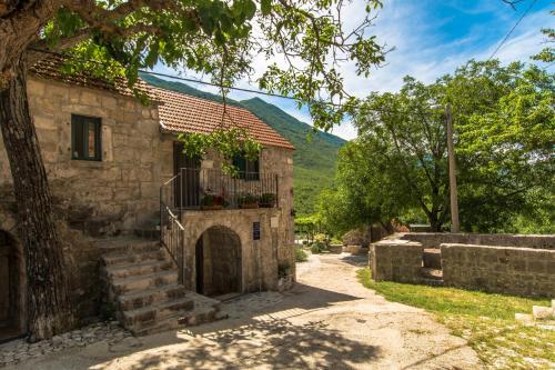 ein altes Steinhaus mit einem Balkon und einer Treppe in der Unterkunft Holiday Home Godinj in Donje Rašćane