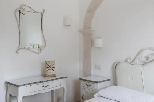 a bedroom with a white bed and a mirror at Villa Angelina in Selva di Fasano