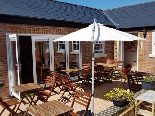 a patio with tables and chairs and an umbrella at Potterspury House in Potterspury