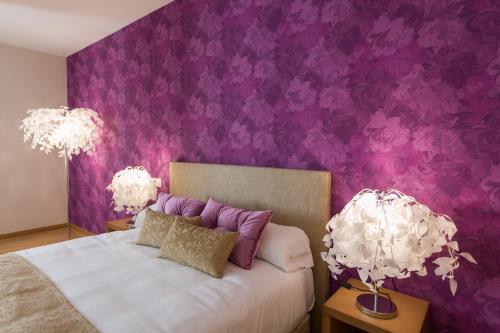 um quarto com paredes roxas e uma cama com 2 candeeiros em Hotel A Roldana em Narón