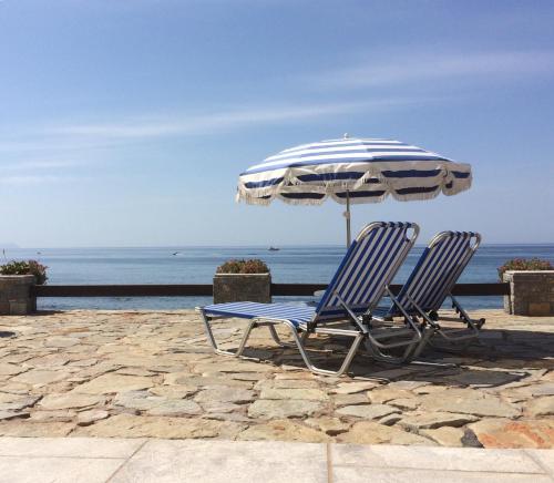 a pair of chairs and an umbrella on the beach at Porto Sisi Hotel Apartments in Sissi