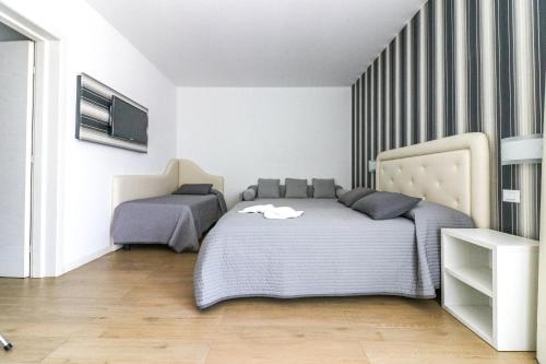 a bedroom with two beds and a tv on the wall at Hotel Jesulum in Lido di Jesolo