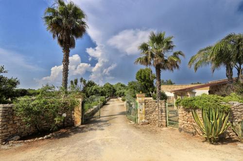 a dirt road with palm trees and a fence at Allu Ruvezzu in Torre Mozza