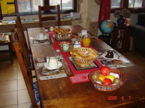 una mesa con alimentos para el desayuno y un bol de fruta en Le Logis du Roc en Granville