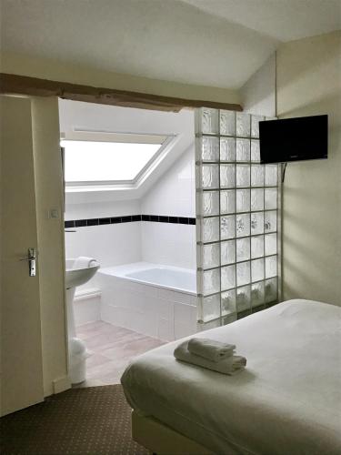 a bedroom with a bed and a bath tub and a television at Logis Hôtel Louise de Savoie in Blois