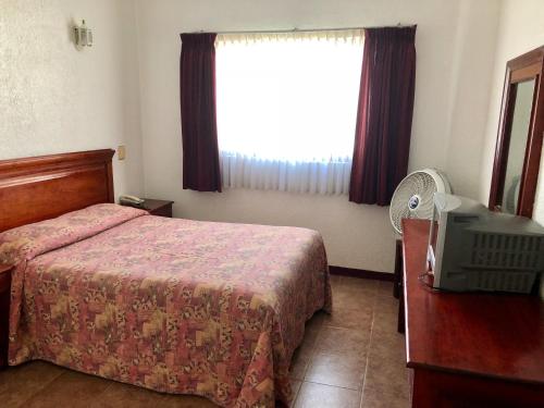a bedroom with a bed and a window and a television at Hotel Roma in Oaxaca City