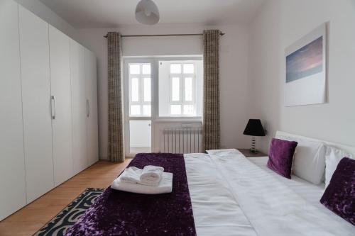 a bedroom with a large white bed with purple accents at The Arc Residence in Astana
