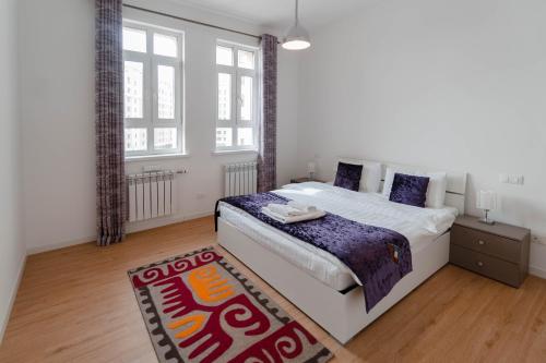 a bedroom with a large white bed and a rug at The Arc Residence in Astana