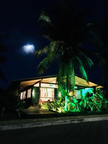 a palm tree in front of a house at night at Pousada Verdes Mares in Fernando de Noronha