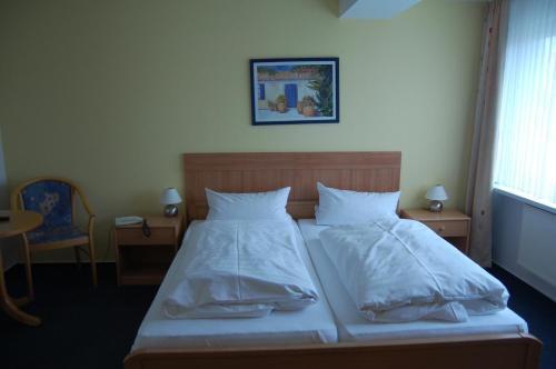 a bed with white sheets and pillows in a room at Hotel Johnel in Hennef