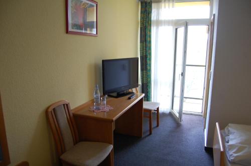 a room with a desk with a television and a window at Hotel Johnel in Hennef