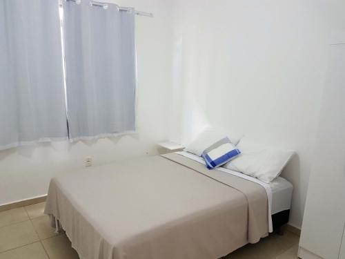 a white room with a bed with a blue book on it at Apartamento no Dalas Park Residencial in Campina Grande