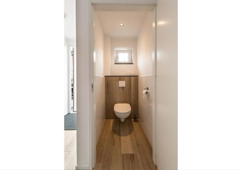 Un pequeño baño con inodoro y ventana. en Holiday Home Zuidstraat 30B, en Westkapelle