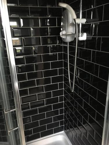 eine Dusche in einem schwarz gefliesten Bad in der Unterkunft Mourne Walks B & B in Annalong