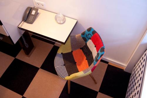 a chair sitting next to a desk with a phone at Hotel Cristall - Frankfurt City in Frankfurt/Main