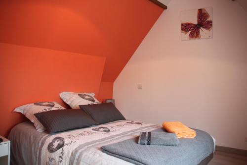 1 dormitorio con paredes de color naranja y 1 cama con 2 toallas en Maison de Tante Louise, en Mittelwihr