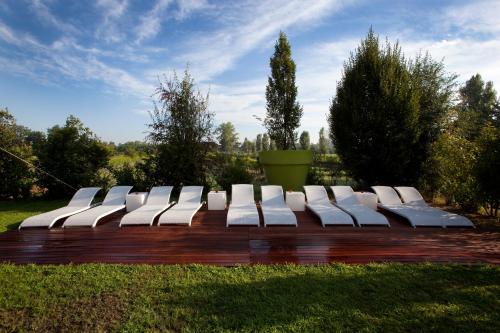 a row of white chairs sitting on a wooden deck at Agriturismo Cascina Caremma in Besate