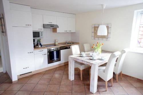 a kitchen with a table and white cabinets at Haus Wyden in Utersum