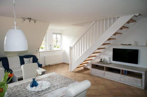 a living room with a television and a staircase at Haus Wyden in Utersum