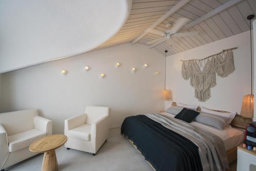 a bedroom with a bed and two white chairs at Yacht Boheme Hotel-Boutique Class - Adults Only in Fethiye