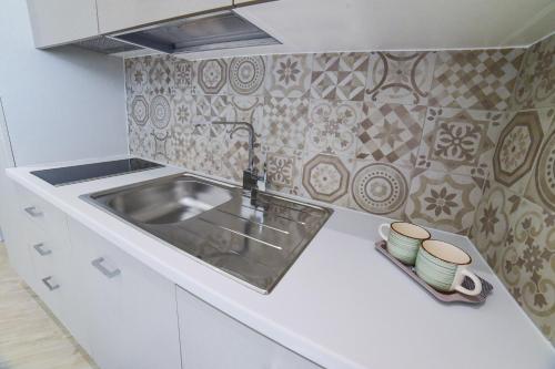 a kitchen with a sink and a tile wall at Lux apartments in Porto Cesareo