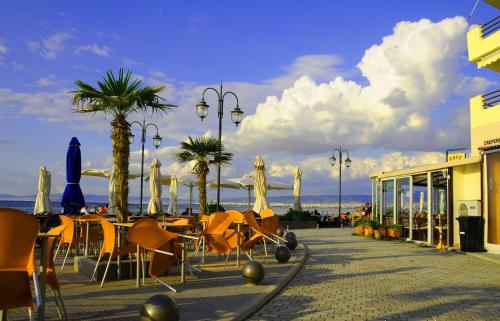a group of tables and chairs with umbrellas and palm trees at Hotel Avra in Perea