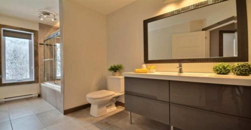 uma casa de banho com um lavatório, um WC e um espelho. em Harfang des Neiges Mont-Blanc By Rendez-Vous Mont-Tremblant em Saint-Faustin