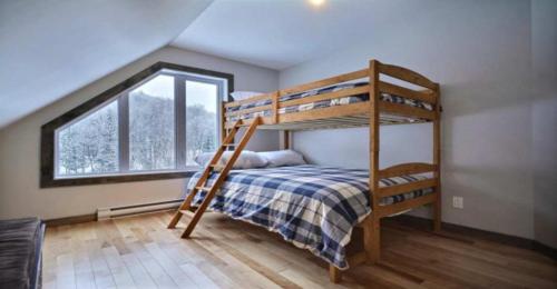 a bedroom with two bunk beds and a window at Harfang des Neiges Mont-Blanc By Rendez-Vous Mont-Tremblant in Saint-Faustin