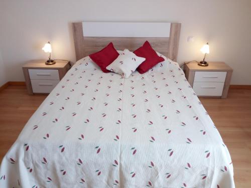 a bed with a white comforter and red pillows at Fun & Sun Apartment in Olhão