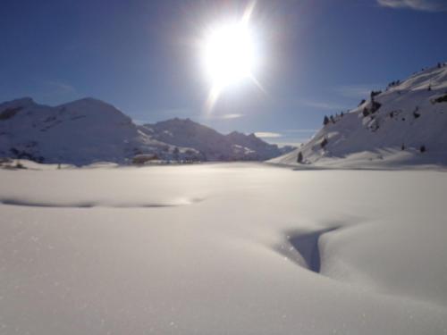 a snow covered river with the sun in the background at Apartments Bogensperger in Mariapfarr