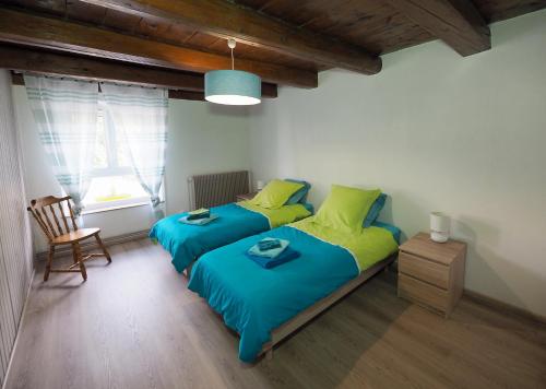 1 dormitorio con 2 camas individuales y 1 silla en La ferme aux volets bleus, en Mainvillers