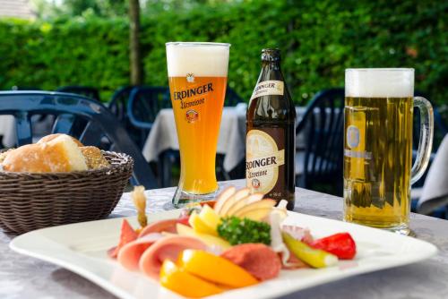 un tavolo con un piatto di cibo e due bottiglie di birra di Gasthof Ziegler Hotel & Restaurant a Lindau