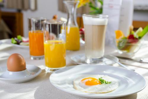 an egg on a plate on a table with drinks at Gasthof Ziegler Hotel & Restaurant in Lindau