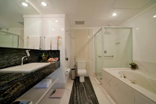 a bathroom with a tub, sink, and shower at Quality Hotel Vitória in Vitória