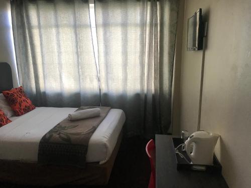 a bedroom with a bed and a window with curtains at Businessburg Hotel in Johannesburg