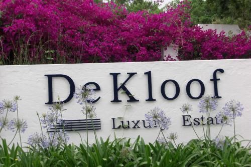 a sign in front of some purple flowers at De Kloof Heritage Estate and Wellness in Swellendam