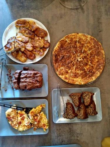 a table with three plates of food and a pizza at Thalia Traditional Guest House in Promírion