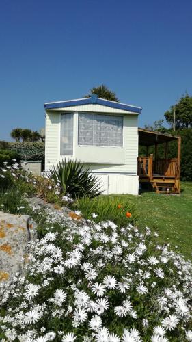 una pequeña casa blanca con flores blancas en el patio en Mobil home vacances, en Plouguerneau