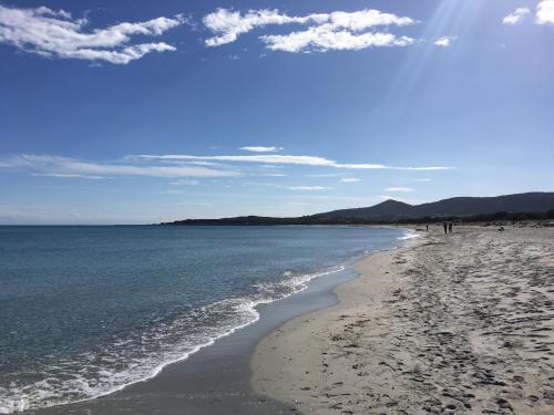 a beach with people walking on the sand and the water at Sa Murta Bianca Guesthouse in Budoni